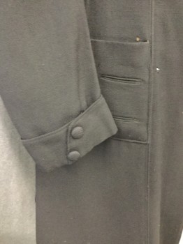 N/L, Black, Wool, Silk, Solid, Middle Class Coat. Black Gabardine with Velvet Collar, Notched Lapel, 4large Covered Button Front, 2 Patch Pockets with 2 Buttons, Cuff on Sleeve with 2 Small Covered Buttons, 3 Slits at Back of Coat/ Sleeves Gathered to Shoulder. Wearing on Left Cuff. Hole Near Back Right Slit